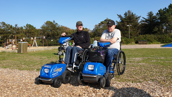 Blå hjælpemotor til kørestol på græs
