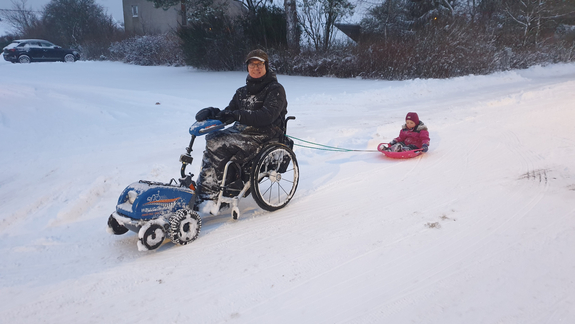 Hjælpemotor til kørestol i sne med kælk spændt fast bagpå